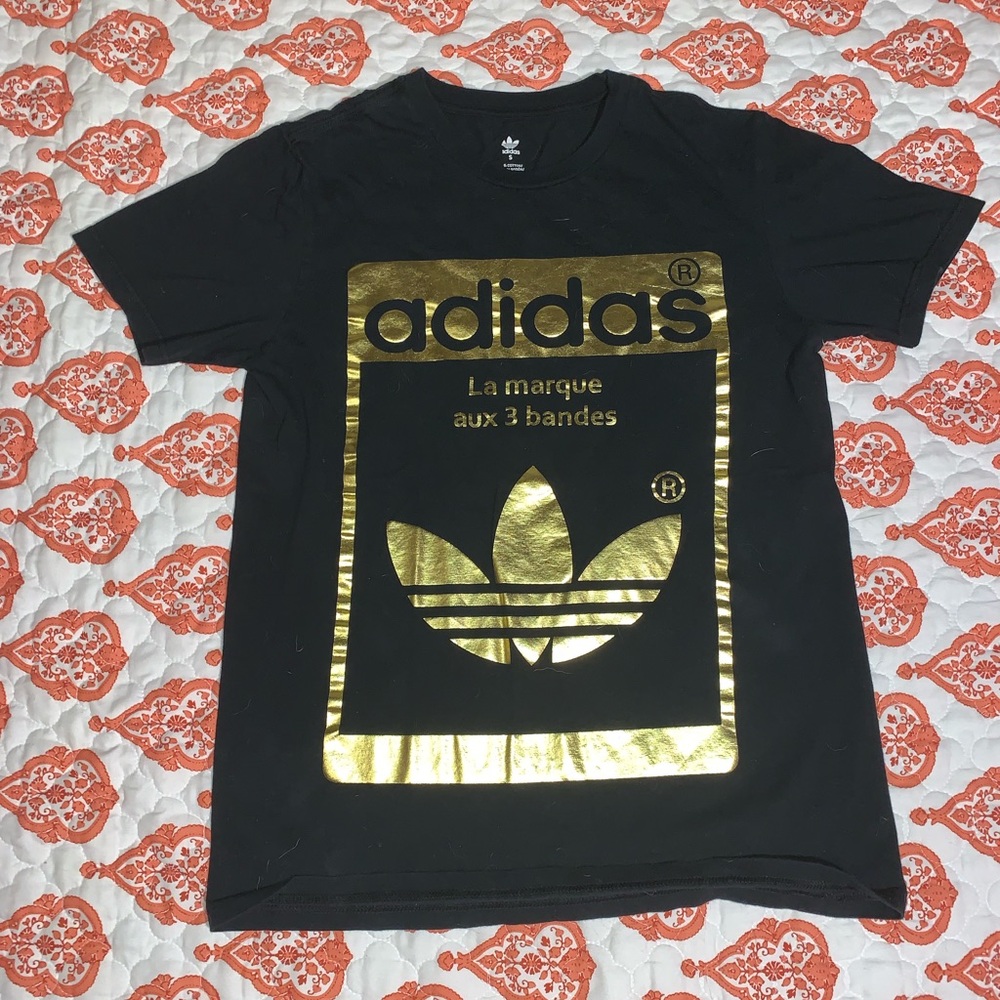 An adidas gold outlined shirt mainly black.